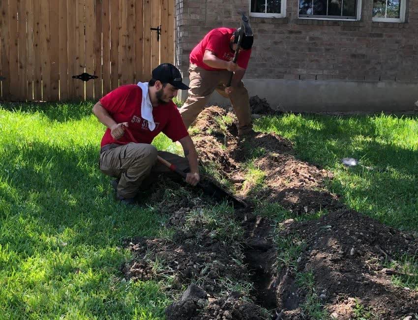 Crew digging a trench for a sewer line repair